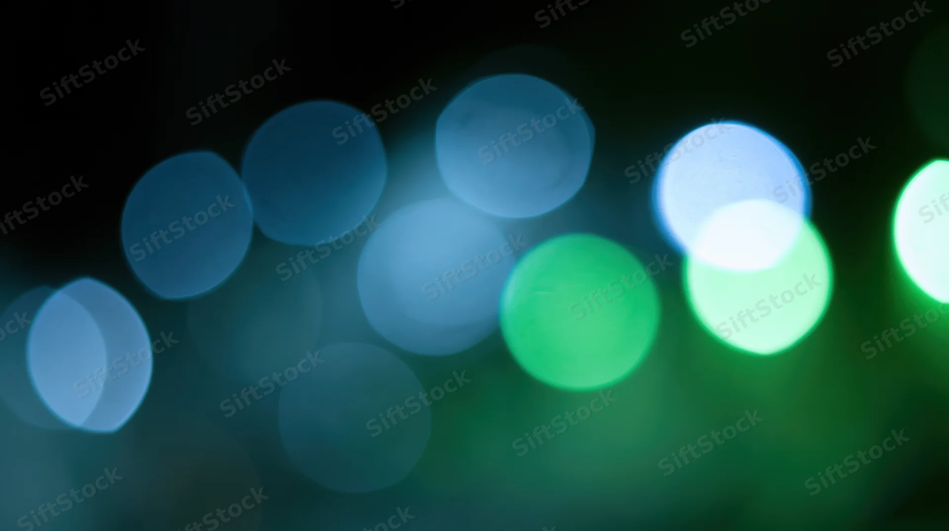 Blurred circular lights in blue and green tones against a dark background