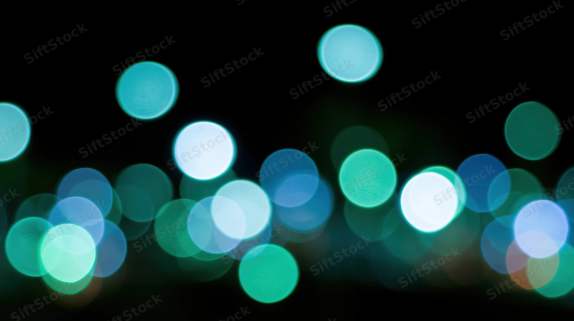 Scattered out-of-focus lights in teal blue and green against dark background