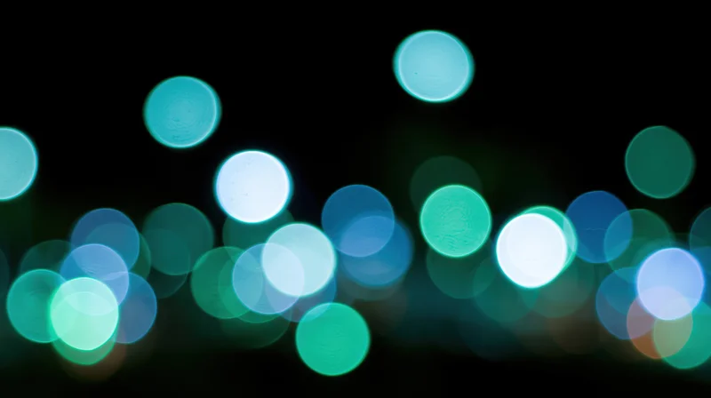 Scattered out-of-focus lights in teal blue and green against dark background