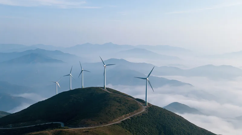 Five wind turbines on a mountain ridge above a sea of clouds