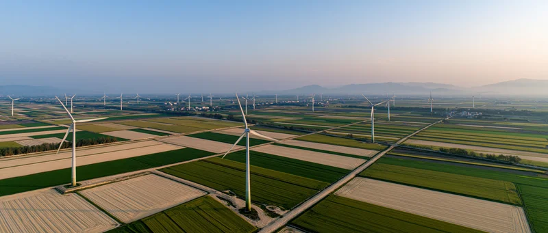 Aerial view of wind turbines scattered across cultivated fields in rural countryside