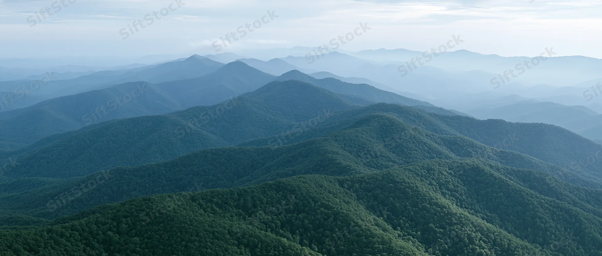 Aerial view of layered green forested mountains stretching into the distance