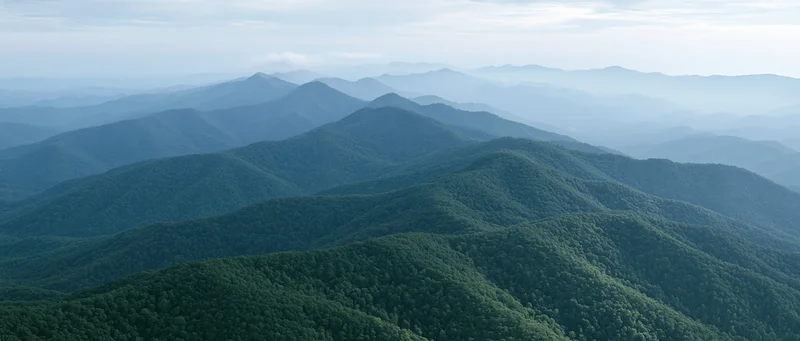 Aerial view of layered green forested mountains stretching into the distance
