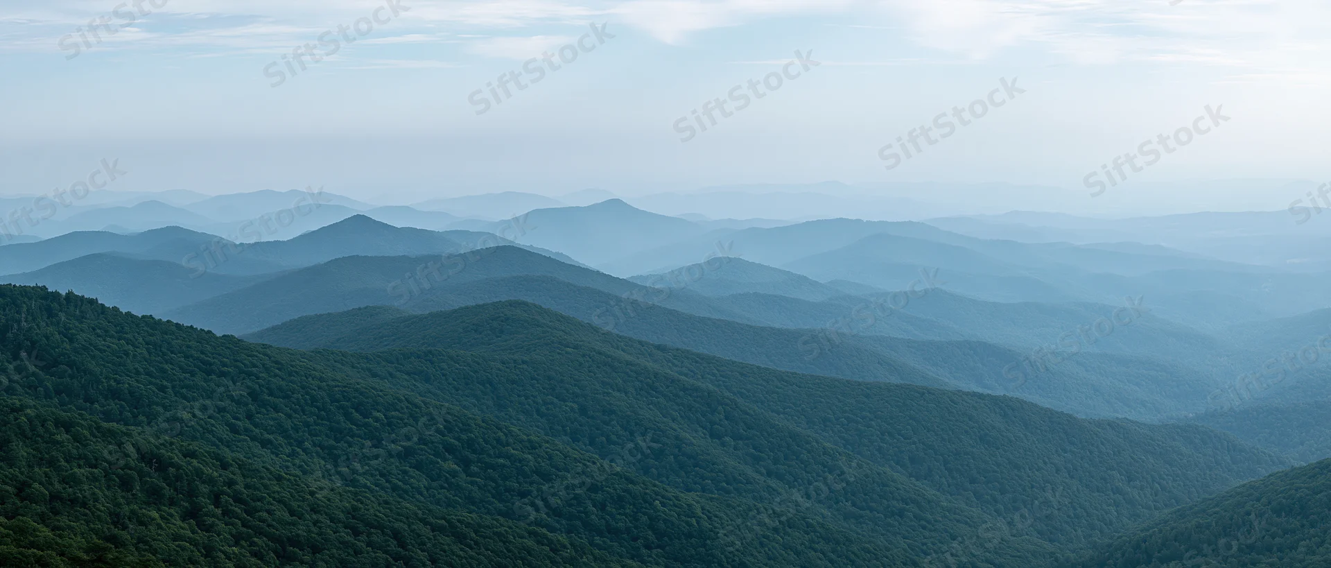 Aerial view of layered green forested mountains stretching into the distance