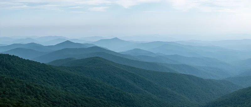 Aerial view of layered green forested mountains stretching into the distance