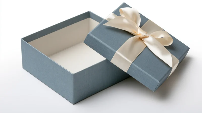 Open blue gift box with cream satin ribbon bow on white background