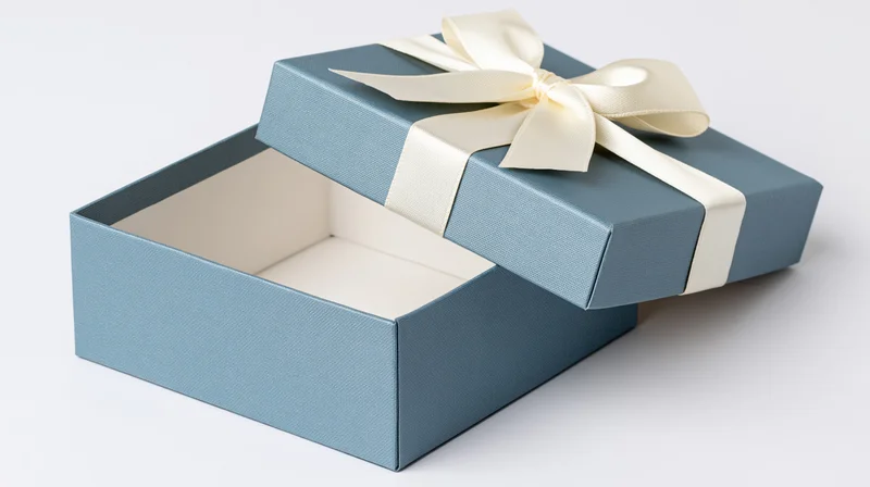Open blue gift box with cream ribbon bow on white background