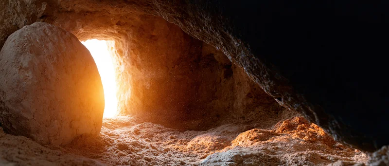 Ancient tomb entrance with large round stone blocking the doorway, illuminated by light from outside