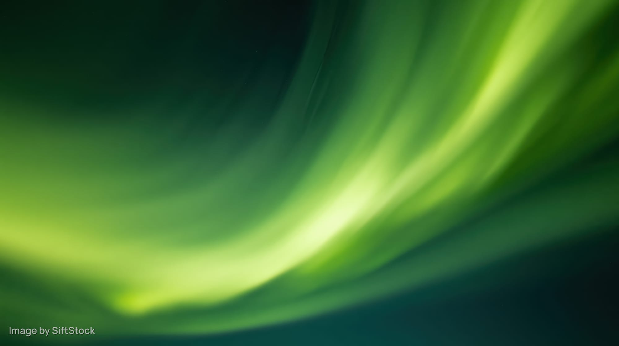 Swirling green aurora borealis lights across dark night sky over open tundra