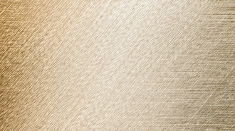 Close-up of a brushed metallic surface with diagonal ribbed texture and warm golden tone