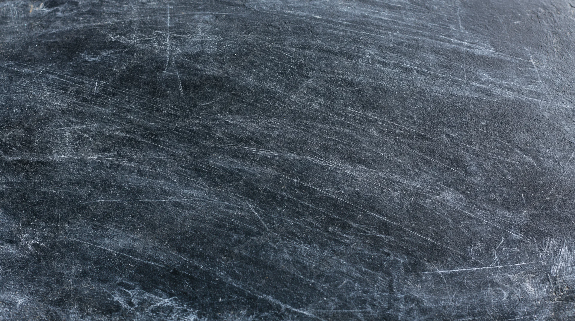 Close-up of a worn blackboard surface with chalk residue and scratches filling the frame