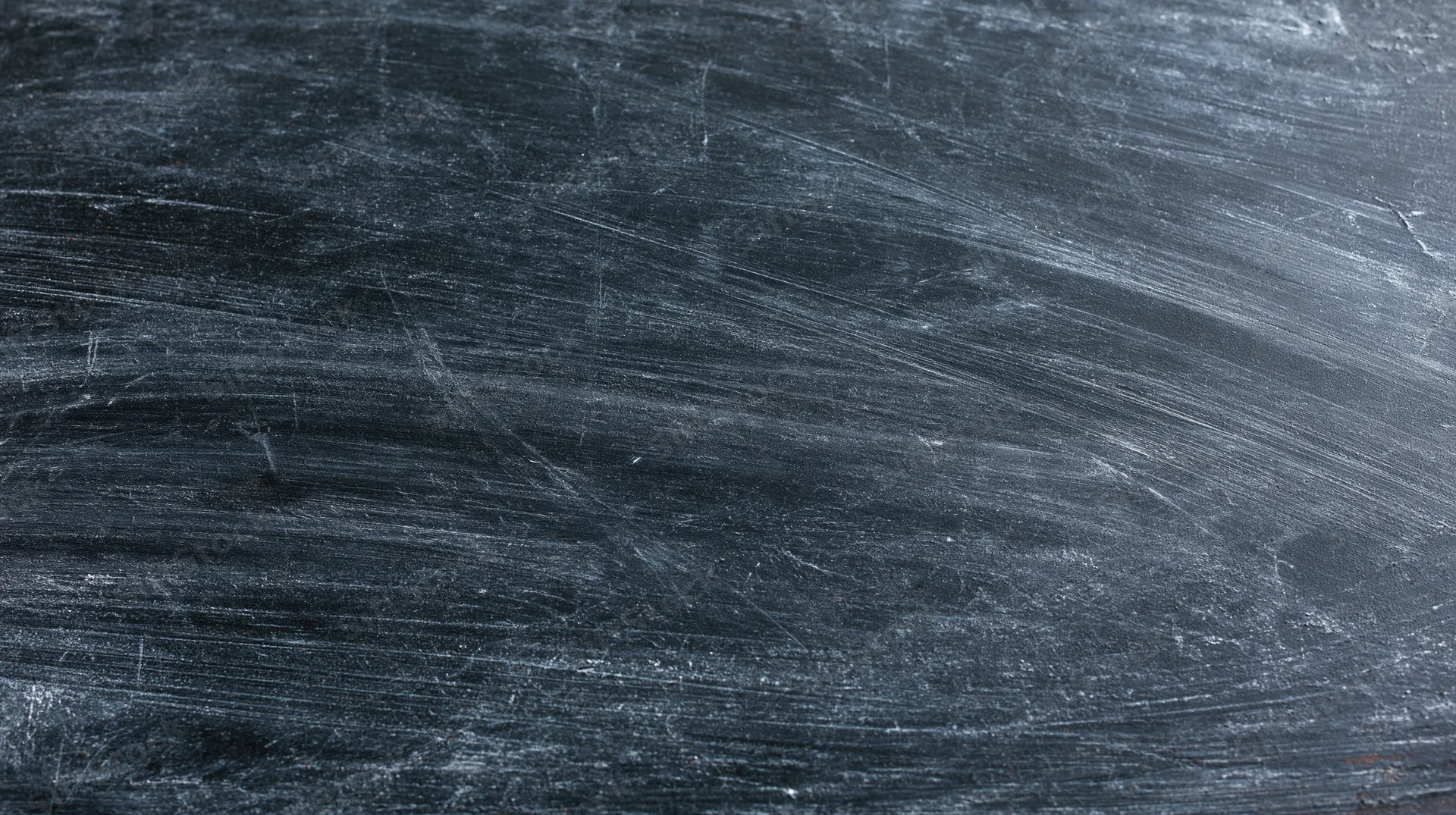 Close-up of a worn blackboard surface with chalk residue and scratches filling the frame