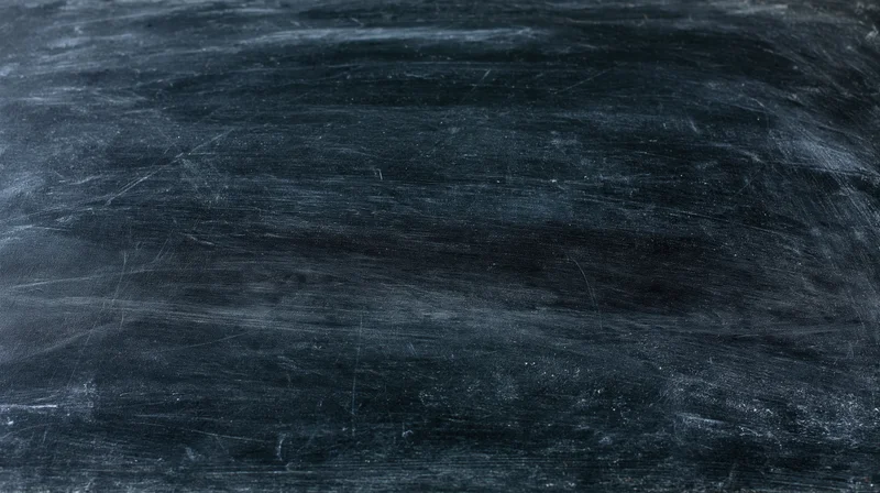 Close-up of a worn blackboard surface with chalk residue and scratches filling the frame