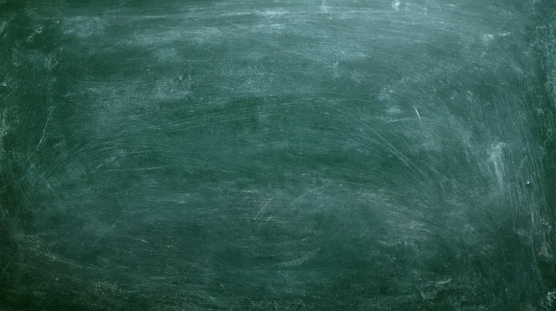 Close-up of a worn dark green chalkboard surface with smudged white residue and scratches