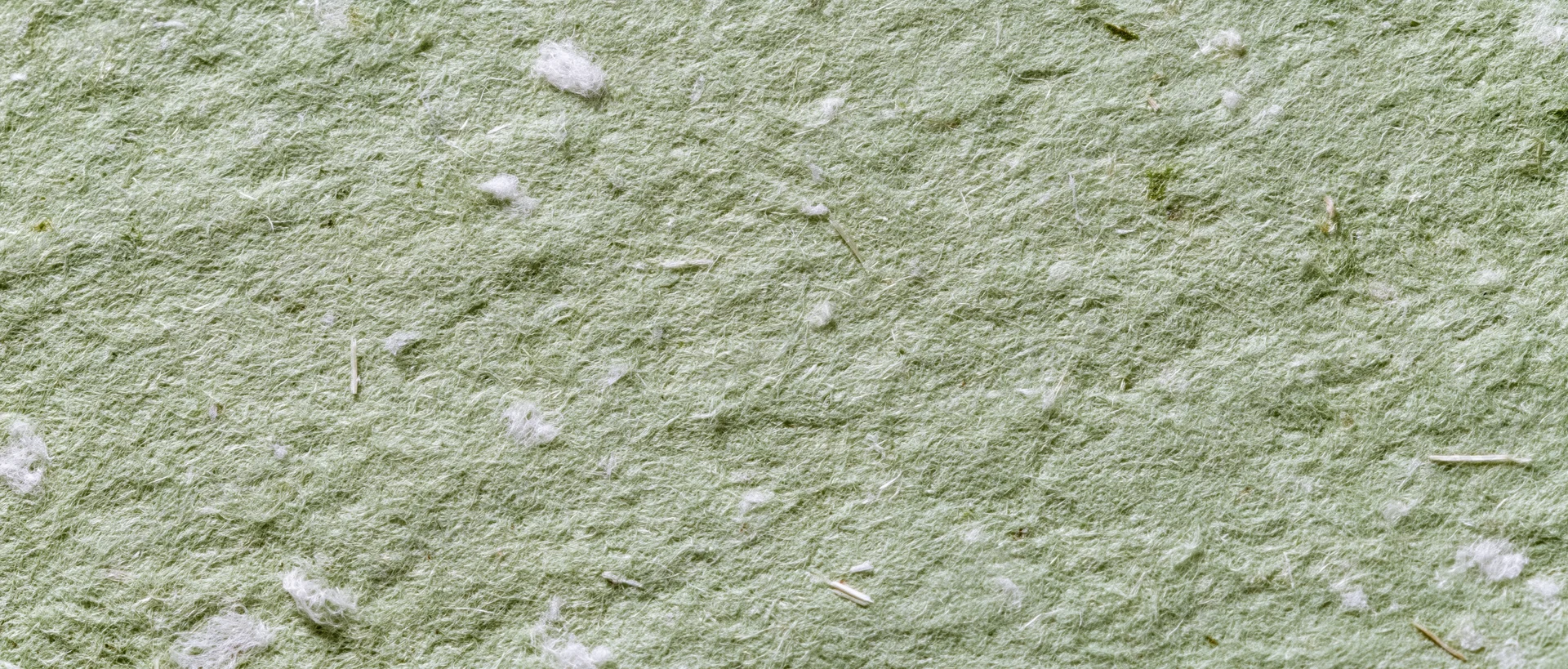 Close-up of sage green handmade paper texture with visible fibers and natural imperfections
