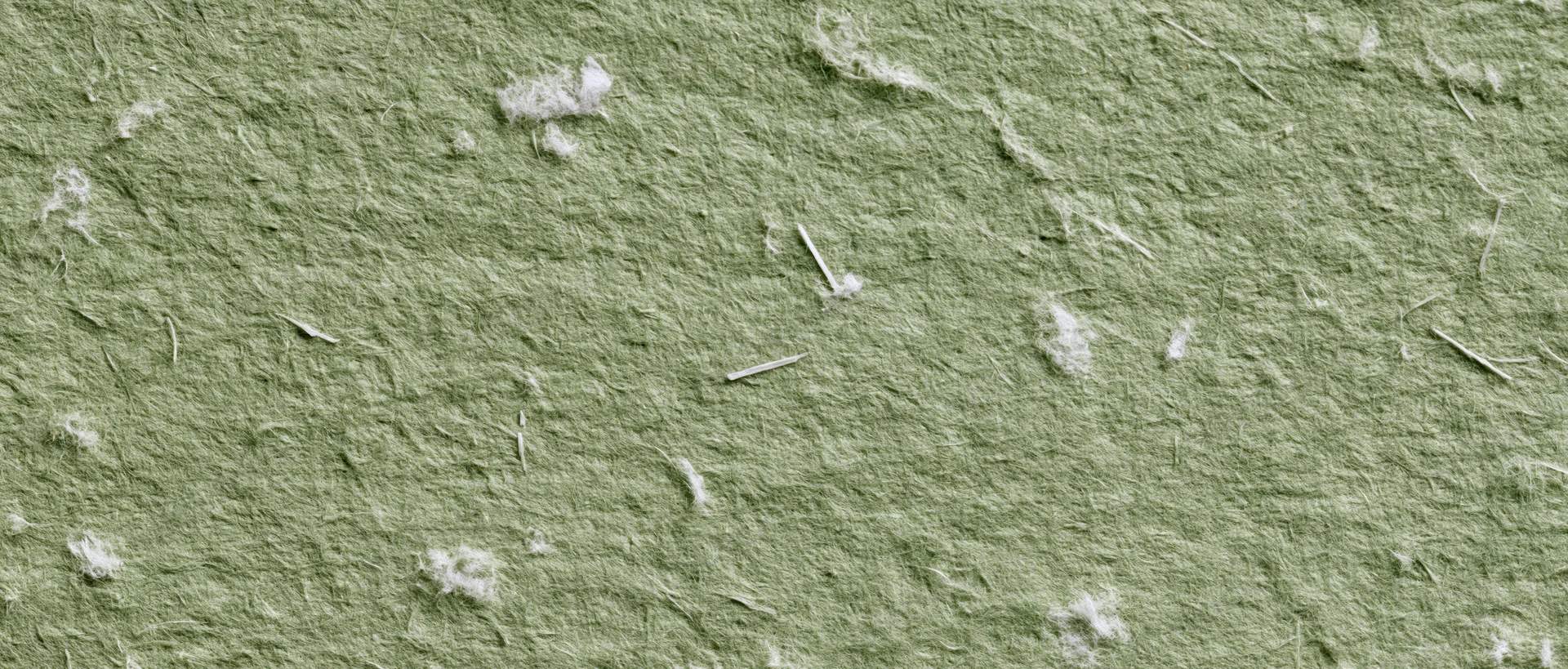 Close-up of sage green handmade paper texture with visible fibers and white flecks