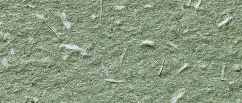 Close-up of sage green handmade paper texture with visible fibers and natural imperfections