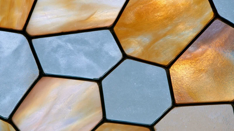 Close-up of hexagonal stained glass window surface with amber and gray panels arranged in a mosaic pattern