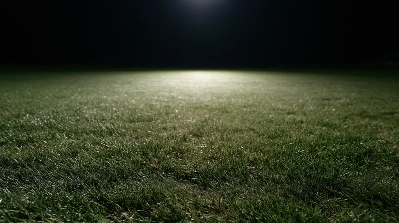 Close-up ground-level view of illuminated grass football pitch at night