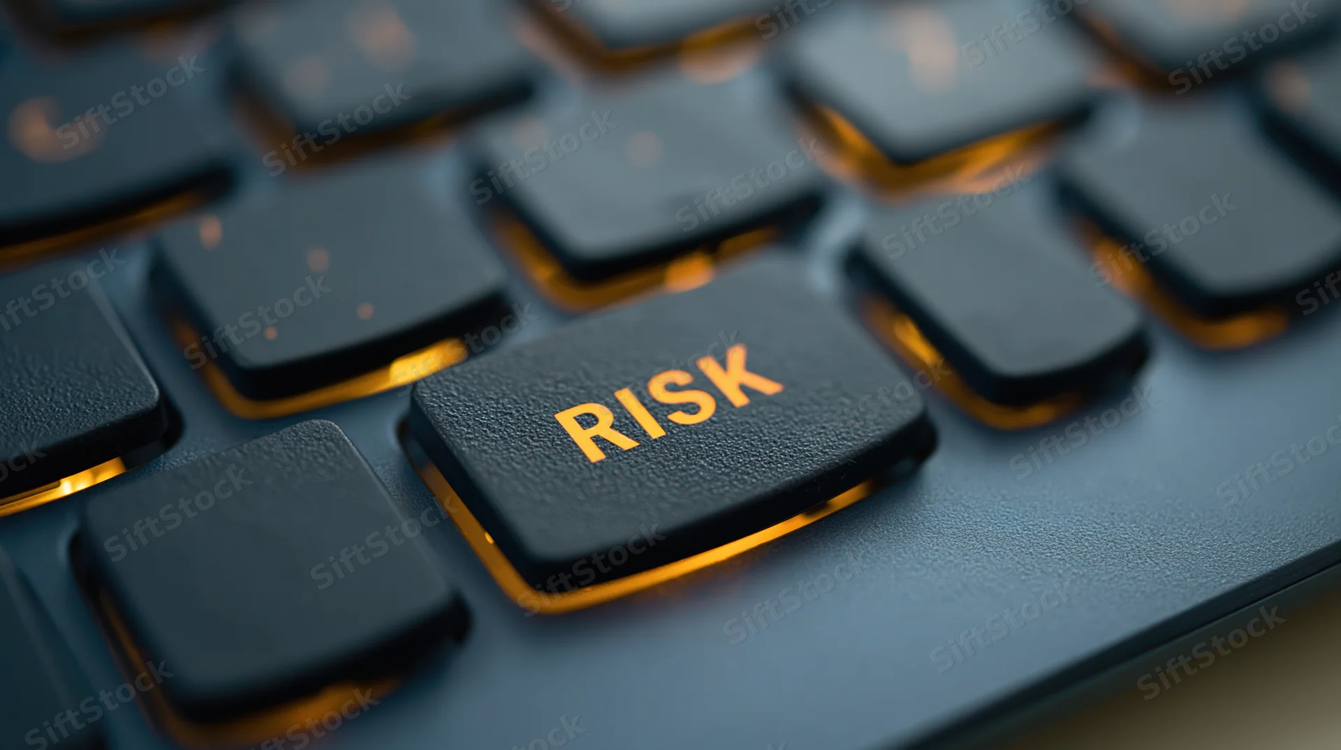 Close-up of a black keyboard with an illuminated key labeled risk