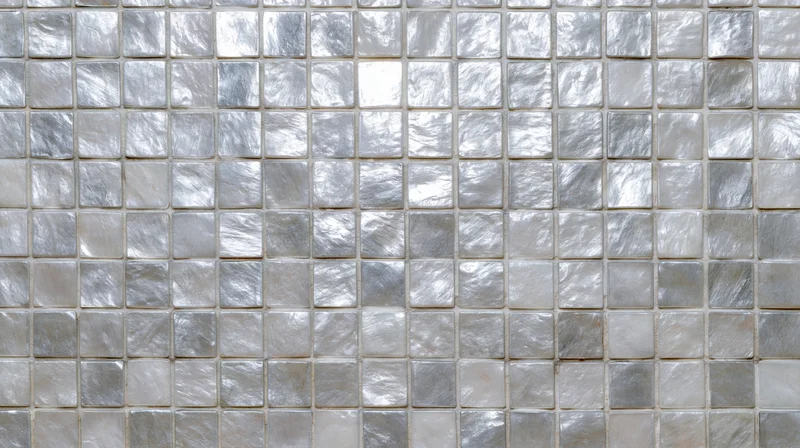 Close-up of silver mosaic tiles arranged in a grid on a wall surface