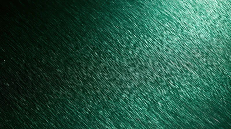Close-up of brushed green metallic surface with diagonal texture and reflective sheen
