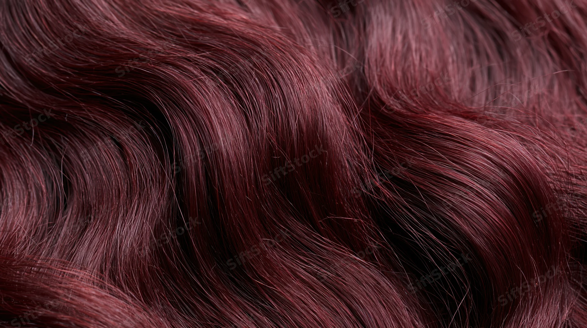 Close-up of deep burgundy wavy hair strands with glossy texture