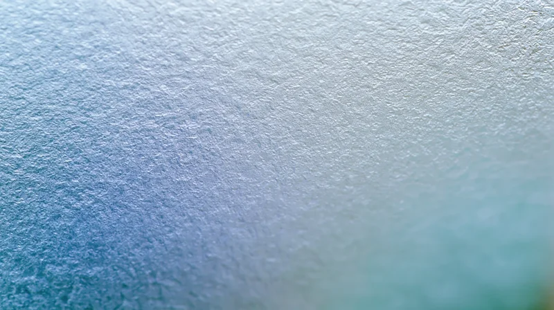 Close-up of frosted glass surface with soft diffused light and blue gradient