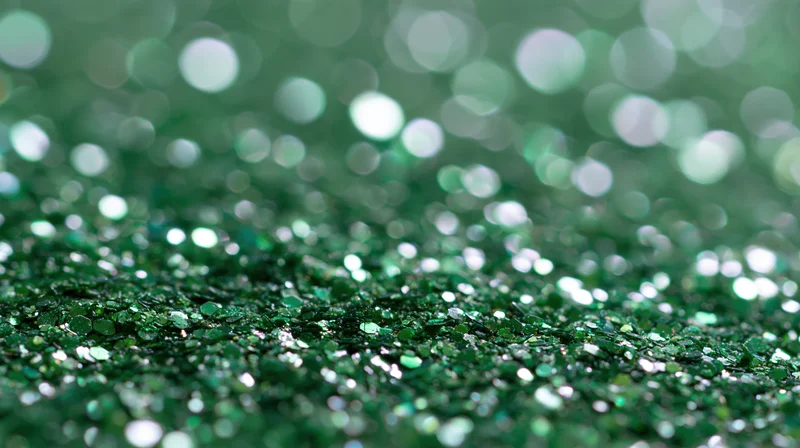 Close-up of green glitter scattered across a flat surface with bokeh background