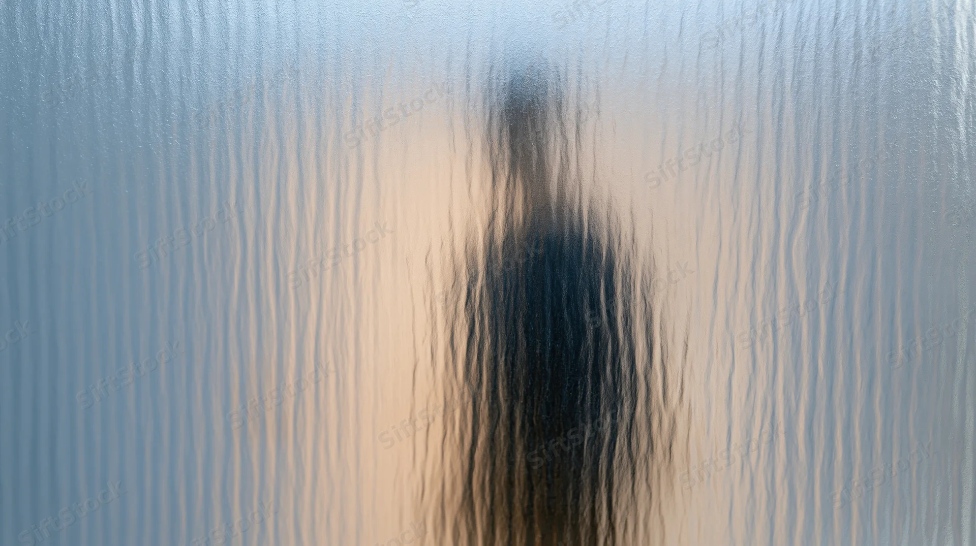 Blurred human silhouette behind ribbed reeded glass panel