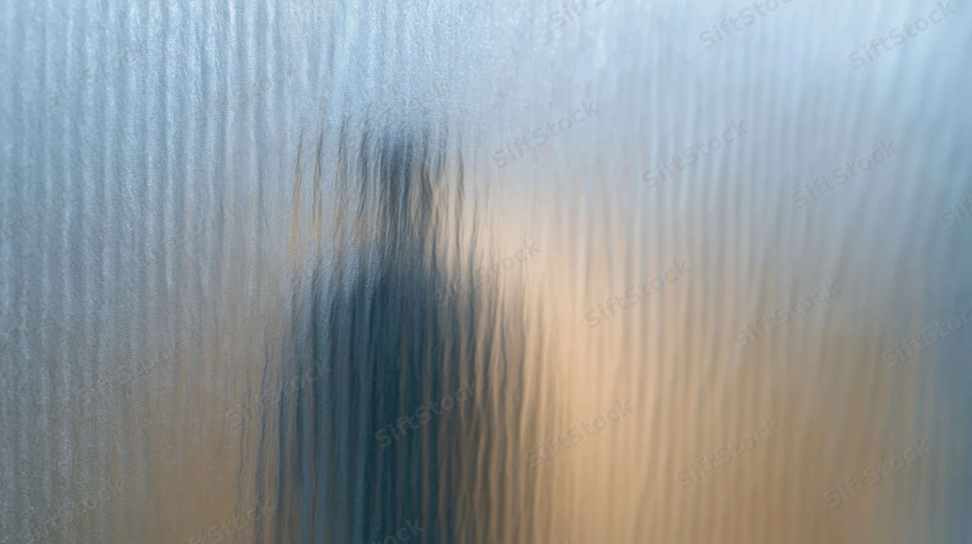 Blurred human silhouette behind ribbed frosted glass panel in interior setting