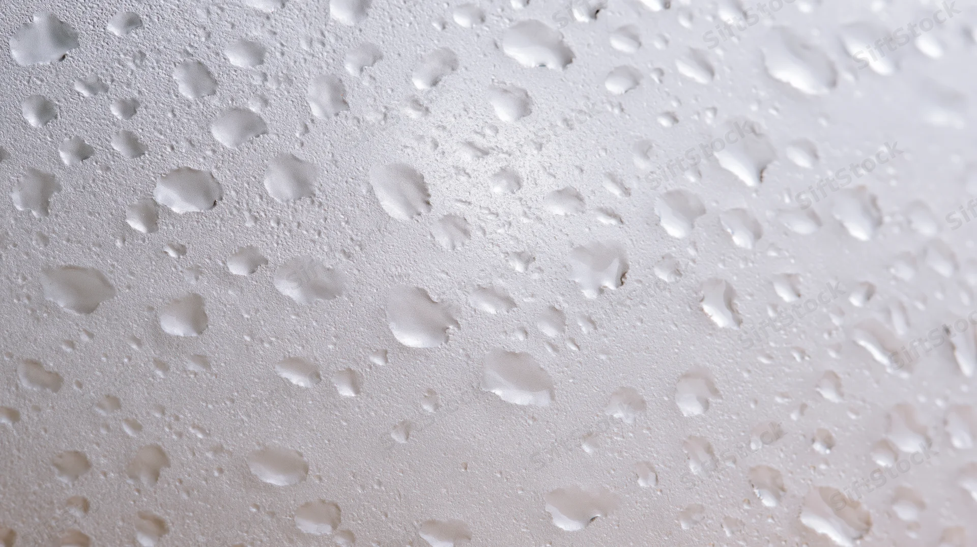 Close-up of water condensation droplets on a smooth white surface