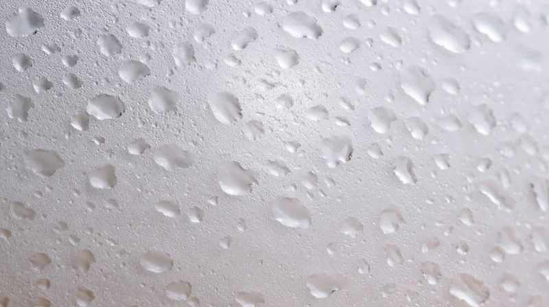 Close-up of water condensation droplets on a smooth white surface