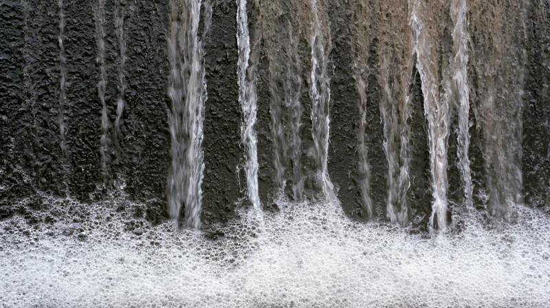 Water streaks and soap foam dripping down a dark textured wall
