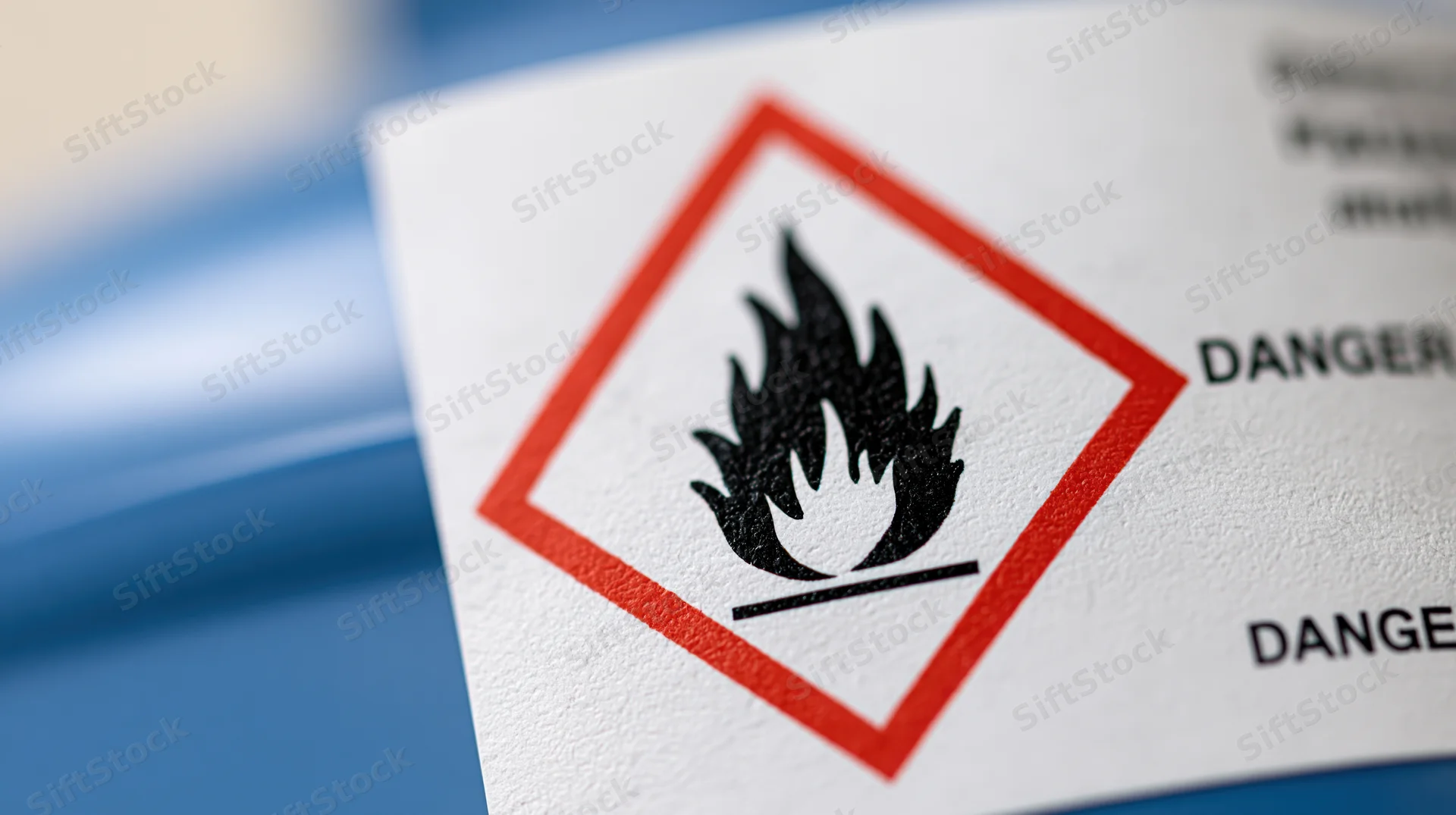 Close-up of a ghs flammable hazard symbol on a white label with red diamond and black flame icon
