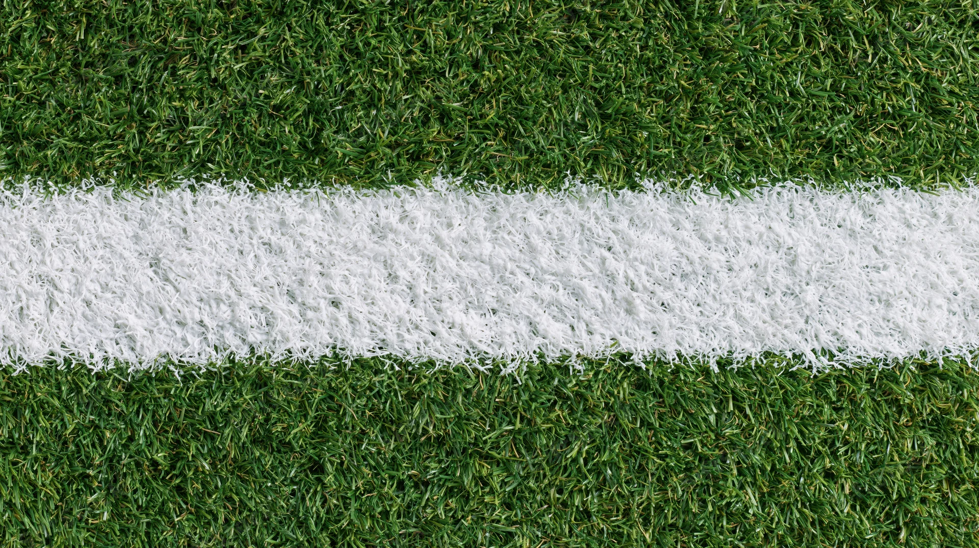 Close-up overhead view of white line on artificial turf sports field
