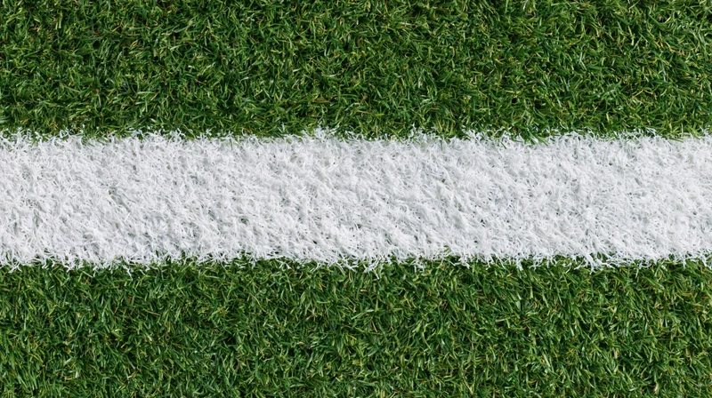 Close-up overhead view of white line on artificial turf sports field