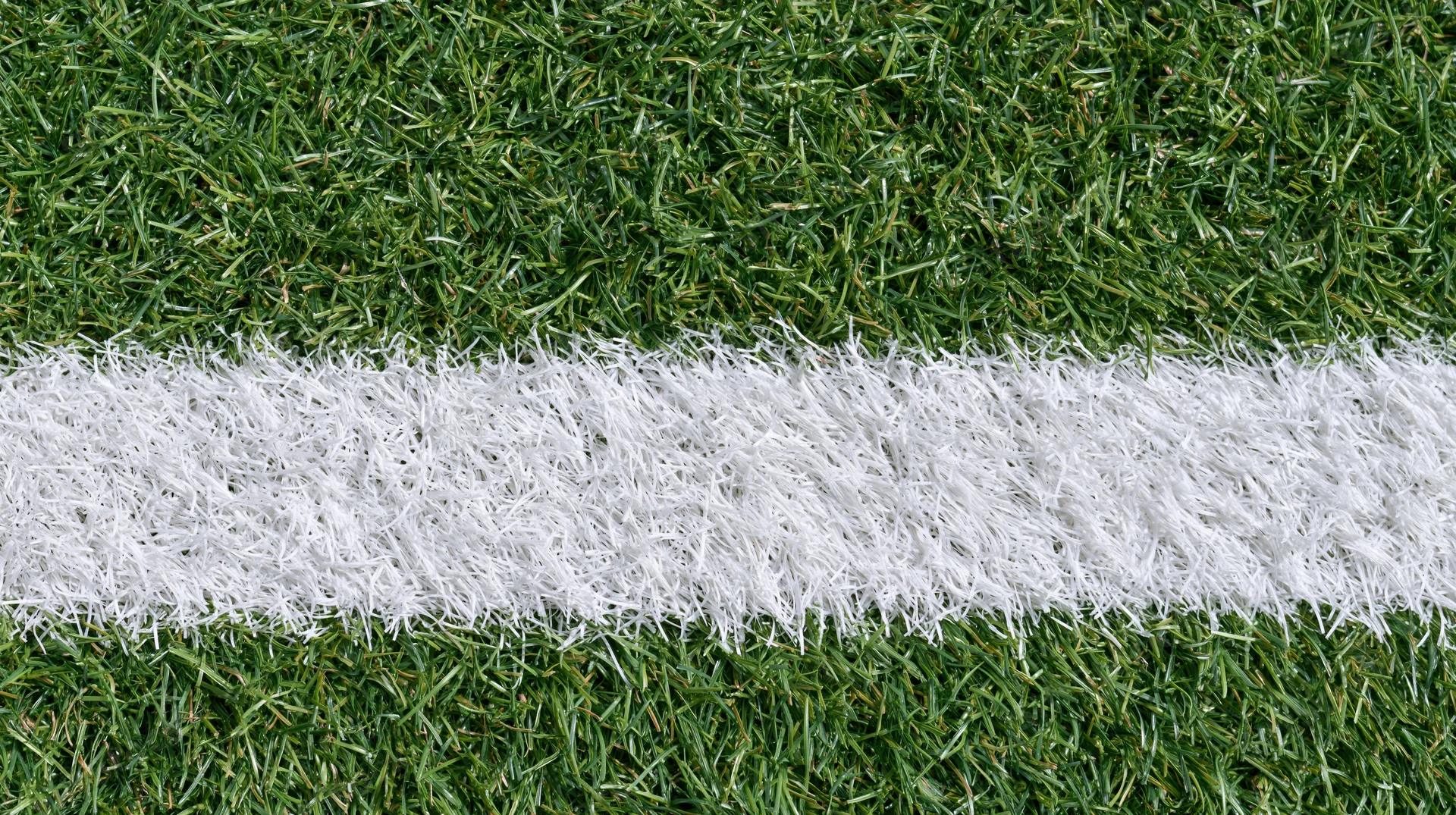 Close-up overhead view of white line on artificial turf sports field
