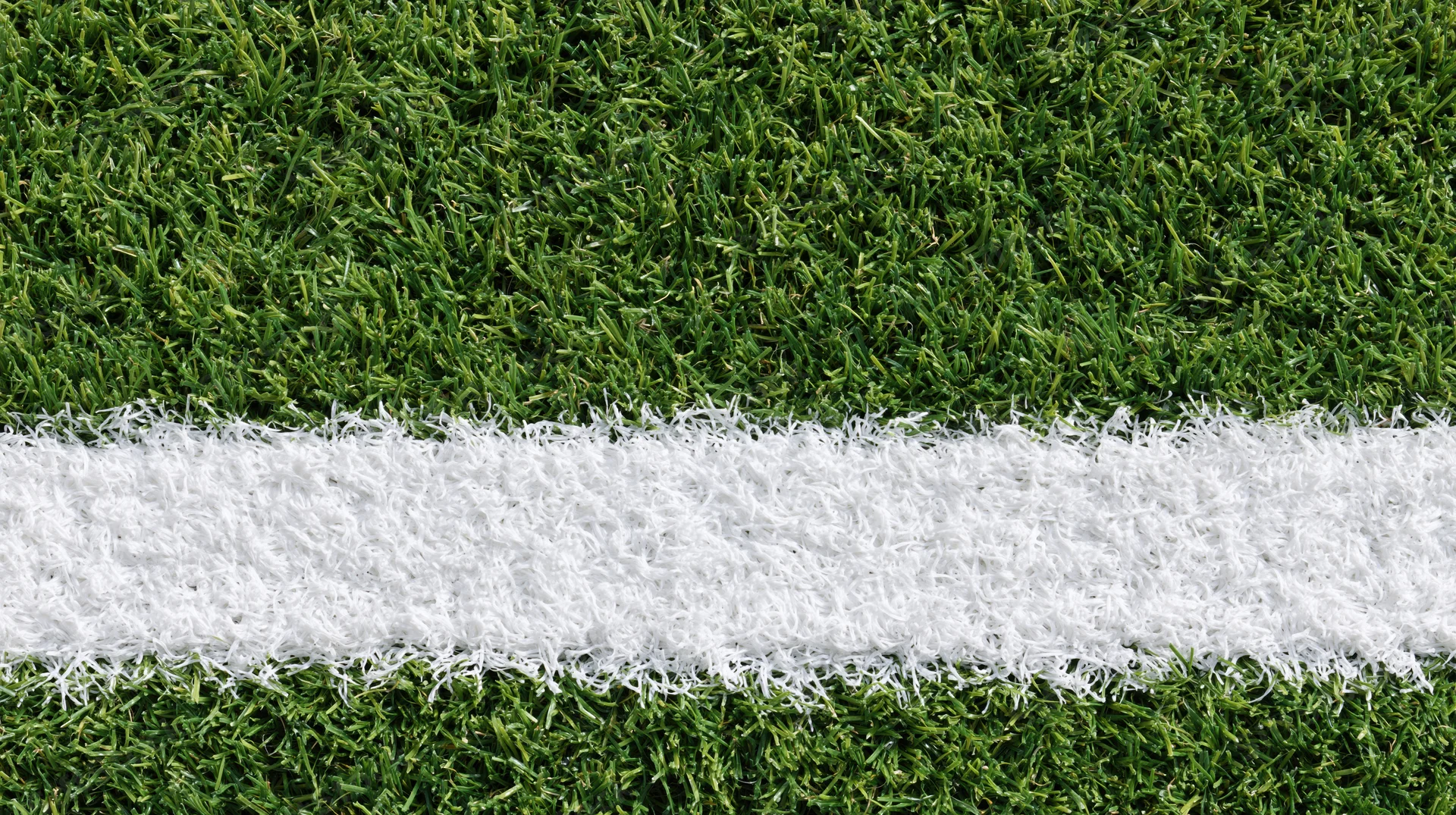 Close-up overhead view of white line on artificial turf sports field