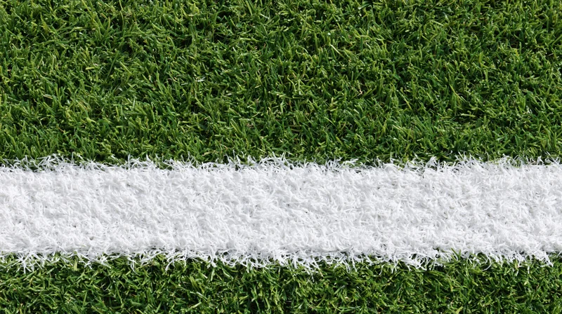 Close-up overhead view of white line on artificial turf sports field