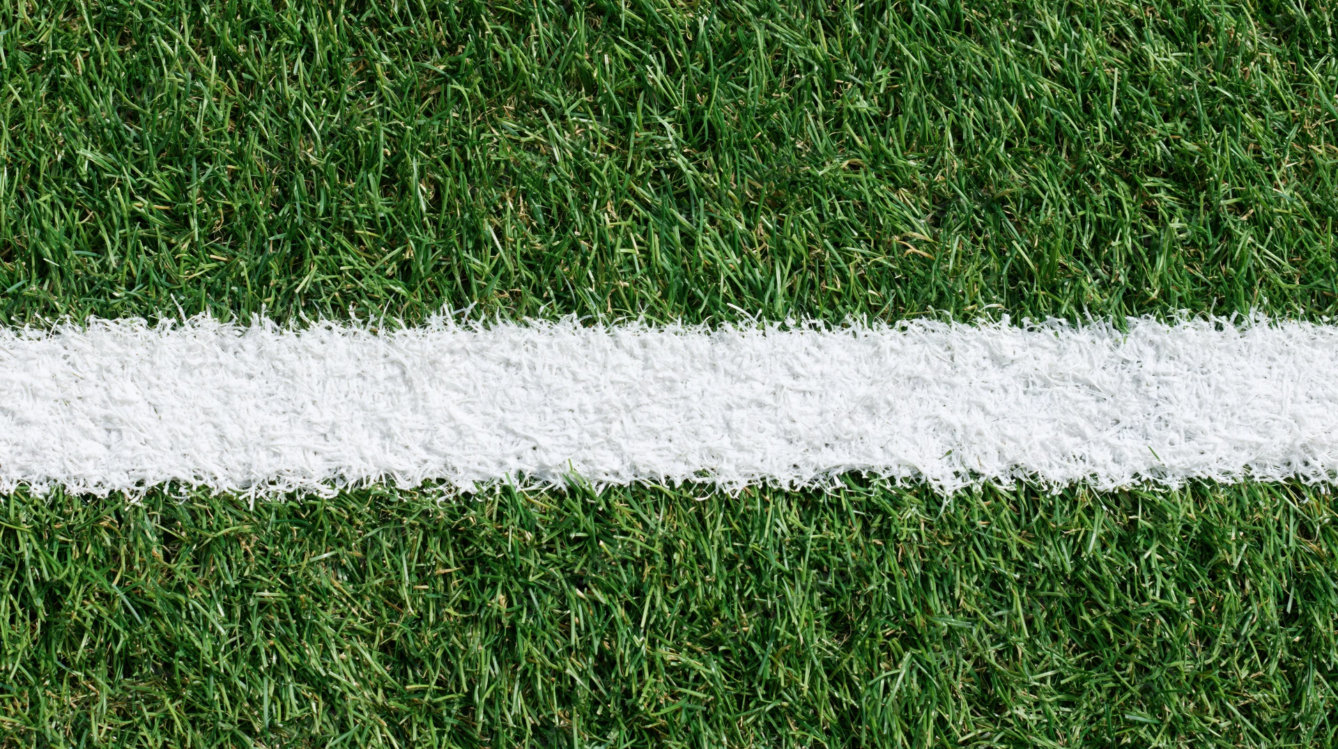 White boundary line on artificial turf sports field viewed from above