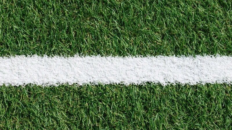 White boundary line on artificial turf sports field viewed from above