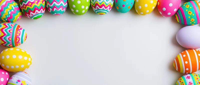 Colorful painted easter eggs arranged in border frame on white surface with copyspace