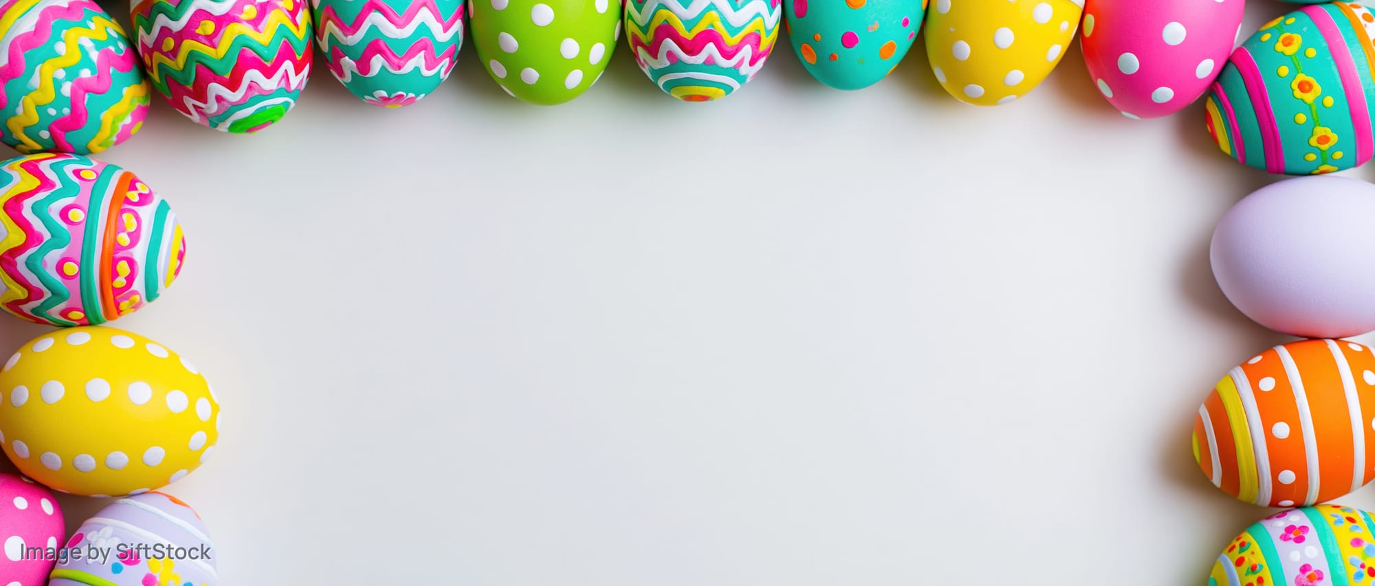 Colorful painted easter eggs arranged in border frame on white surface with copyspace