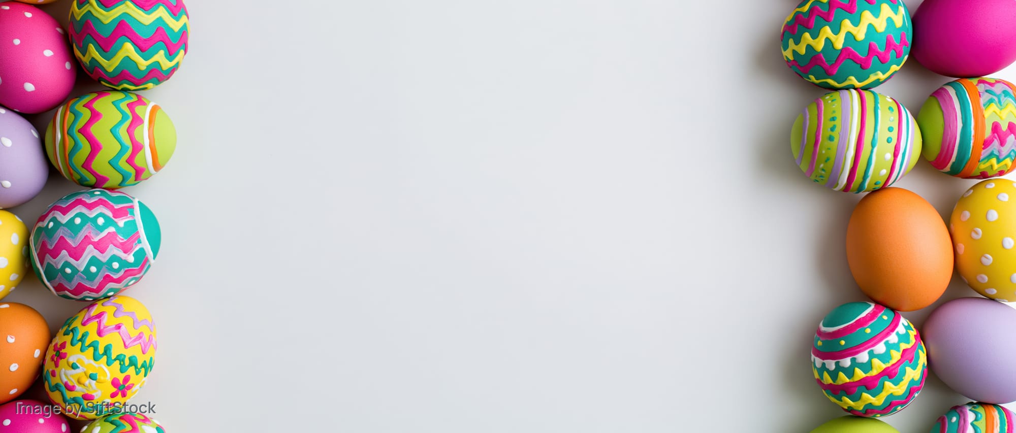 Colorful painted easter eggs arranged in two vertical borders on white surface with central copyspace