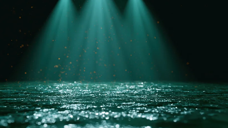 Teal spotlights shining on a dark stage floor with sparkling reflections and floating particles