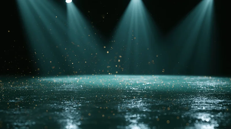 Dark stage floor reflecting teal-green theatrical spotlights with floating particles
