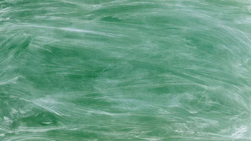 Empty green chalkboard surface with white smudges and erased marks filling the frame