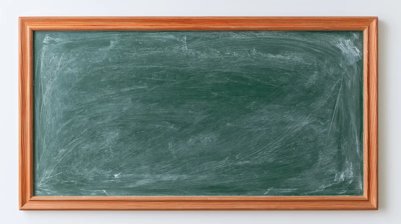 Green chalkboard with eraser smears in wooden frame mounted on white wall