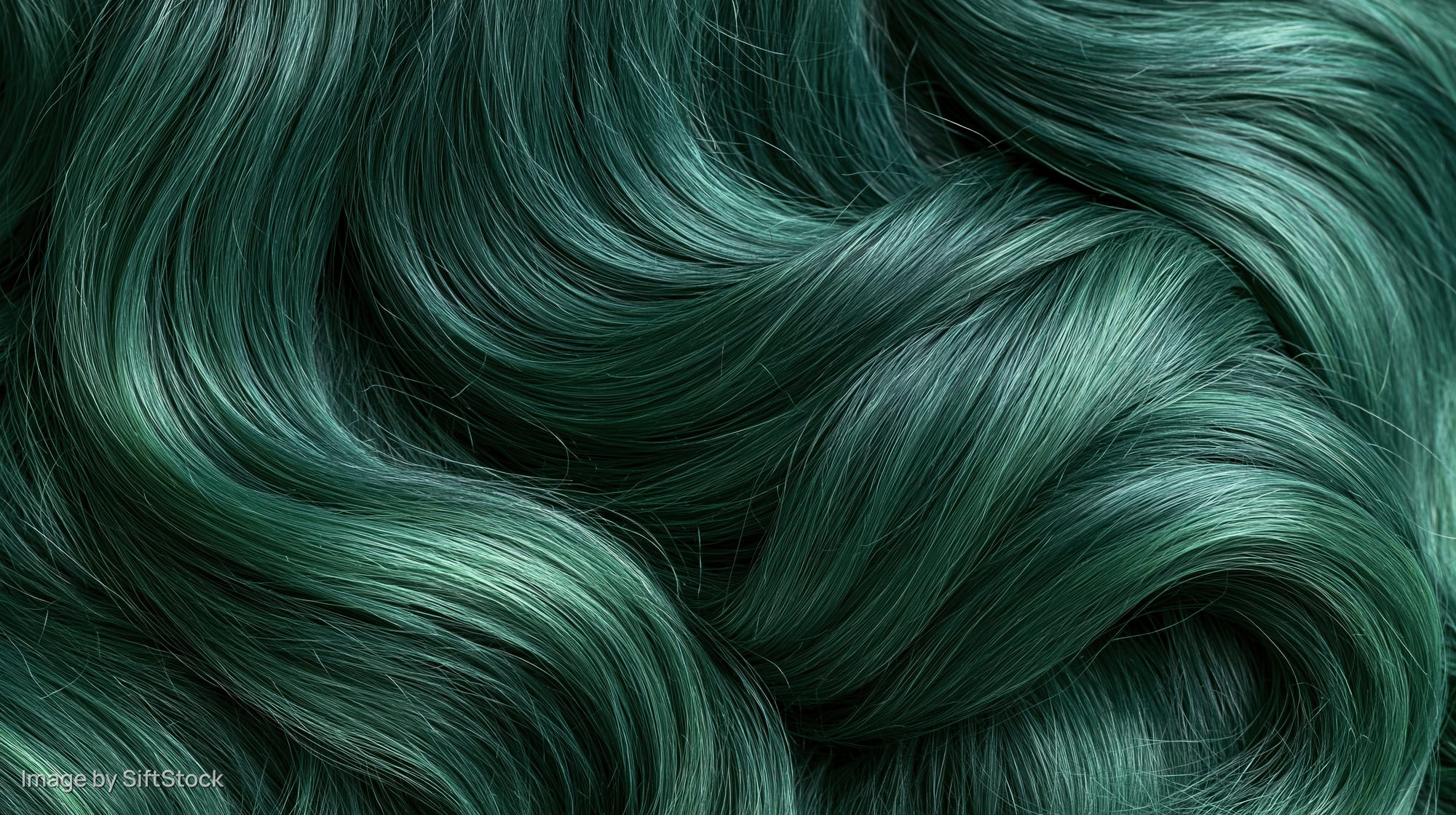 Close-up of wavy emerald green dyed hair with glossy texture